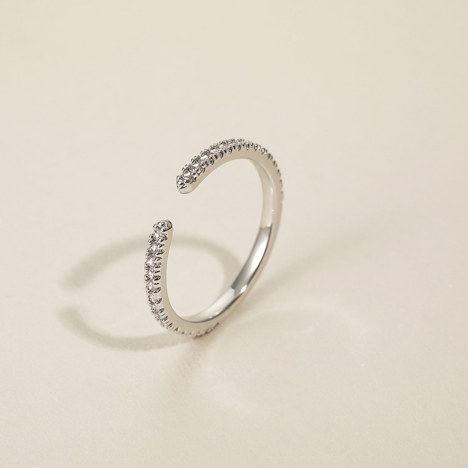 unusual womens wedding bands​, 5A CZ band ring, modern promise ring, cubic zirconia Rings, cz ring, wedding rings cz, eamti rings, cheap wedding rings under $50, copper ring, open band rings, open wedding band​. Silver open ring with embedded stones on a beige background